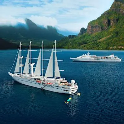 Sailing cruise ship anchored off a green island